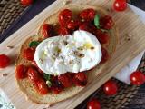 Bruschettone con pomodorini al forno, burrata e pinoli