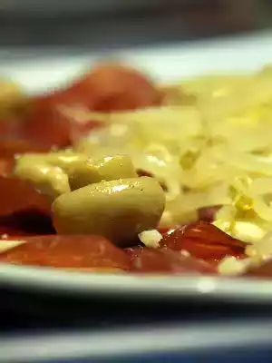 Piatto di bresaola con germogli di soia croccanti, champignons e briciole di grana